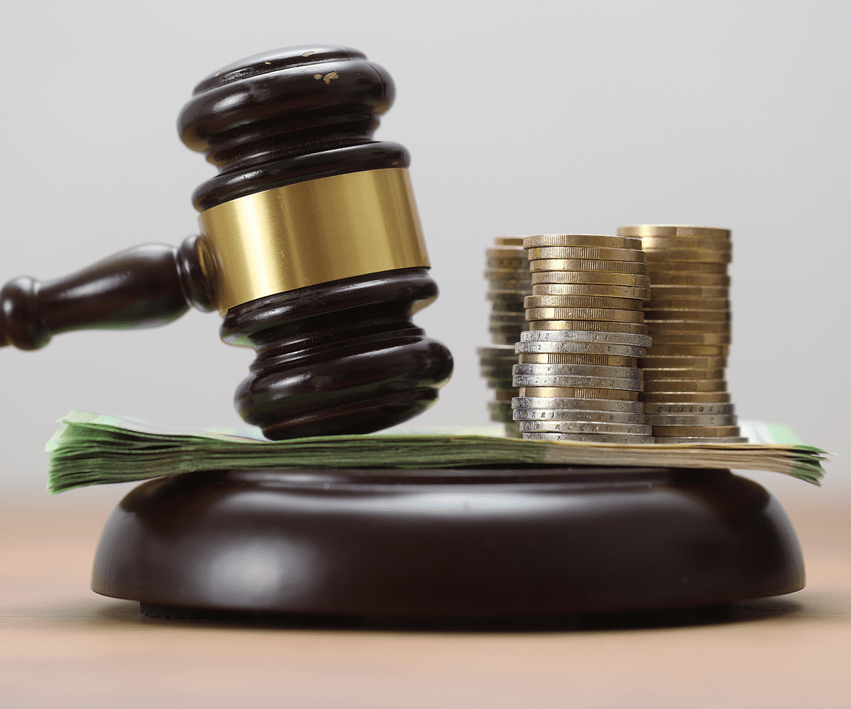 Gavel with coins and cash on table.