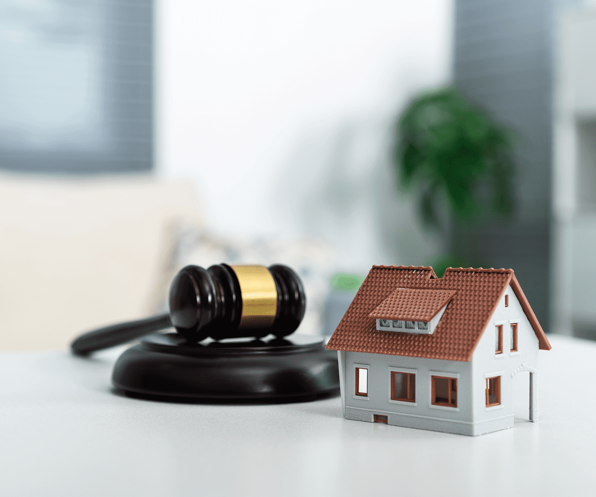 Gavel and house model on table.