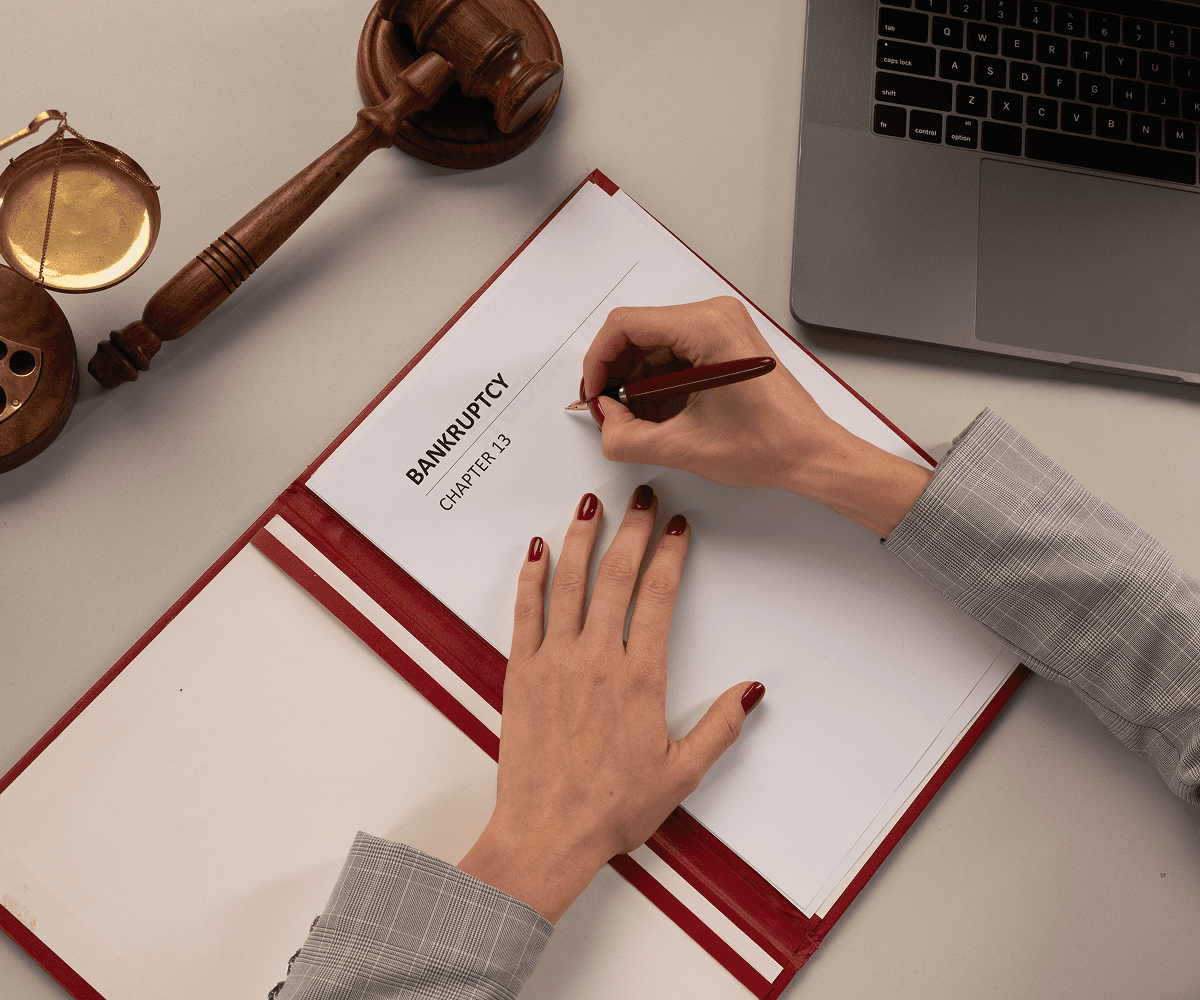 Writing on bankruptcy document with gavel nearby.