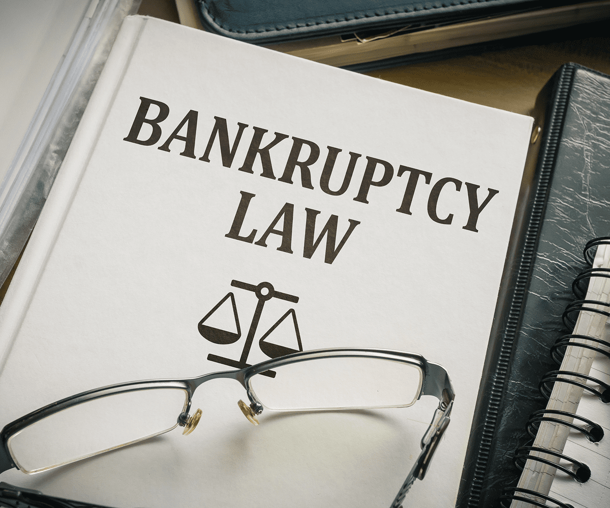 Bankruptcy law book with glasses on table.