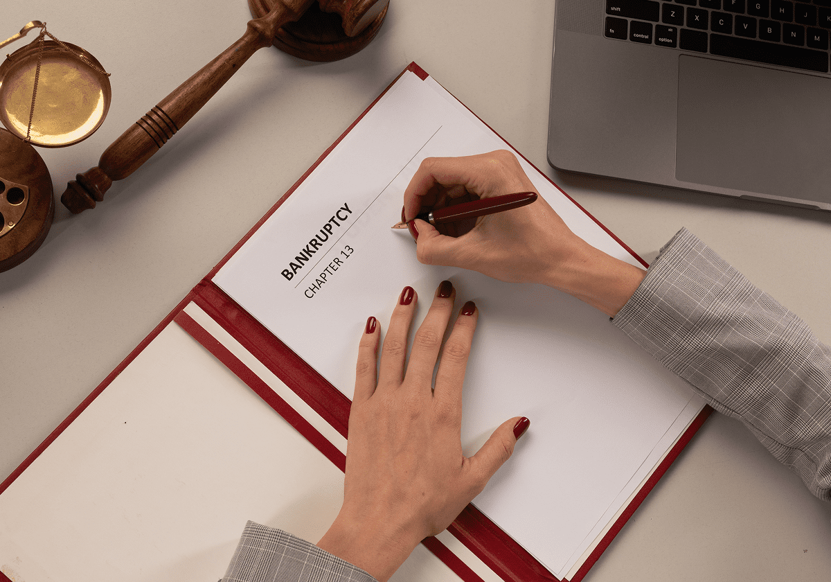 Writing on bankruptcy document with gavel nearby.