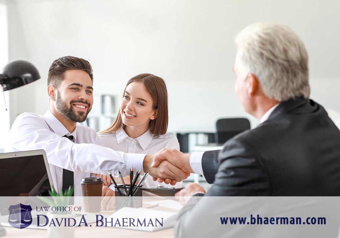 Smiling couple shaking hands with lawyer.