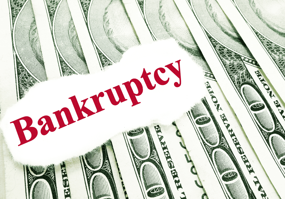 Bankruptcy text on hundred-dollar bills background.
